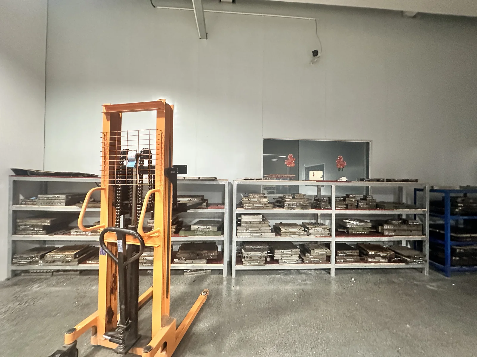 Metal tooling stored on workshop shelves beside a pallet stacker